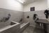 Pet washing station with two tiled tubs, handheld sprayers, a stainless grooming table and wall-mounted pet dryers