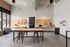 Maker space with a central butcher-block worktable, stools and pegboard walls stocked with tools