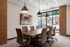 Conference room with a long wood table, upholstered chairs, pendant lights and street-facing windows