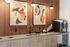 Coffee bar with a sink, specialty coffee machine, wood-paneled wall, globe sconces and abstract art