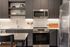 Kitchen with dark cabinets, open shelves, white tile backsplash, stainless steel range, microwave and refrigerator