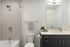 Bathroom with a tiled tub and shower combination, dark vanity, light countertop and mirror