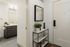 Apartment entry with a keypad smart lock, a console shelf with plants and a view into the bathroom