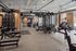 Fitness center with power racks, weight plates, cable stations and cardio machines along exposed brick walls