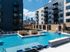 Pool with a tiled water wall and in-water loungers, with apartments and the downtown skyline behind