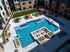 Overhead view of the pool courtyard with a sunken fire lounge, cabanas, loungers, planters and a turf lawn