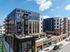 Aerial view of The Wade's corner facade with a terrace, retail storefronts and a Now Leasing banner