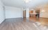 Bright open-concept living room with wooden flooring and a modern kitchen featuring stainless steel appliances.