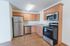 Bright kitchen with modern stainless steel appliances and wooden cabinets.