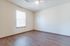 Bright and spacious bedroom featuring wooden flooring, a ceiling fan, and ample natural light through a large window.