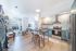 Bright, contemporary apartment with open-plan kitchen and living room, featuring sleek stainless steel appliances and a cozy seating area.