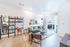 Bright and modern living room featuring a stylish green sofa, chic shelving, and elegant wall art, with ample natural light from large windows.