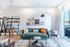 Contemporary living room with a vibrant green sofa, chic gallery wall, and modern shelving exuding style and comfort.