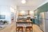 Contemporary open kitchen with sleek green cabinetry, stainless steel appliances, and a cozy dining area, adjacent to a stylish living room with modern decor.