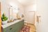 Modern bathroom with sleek green cabinets, granite countertop, and a stylish indoor plant adding a touch of nature.
