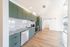 Modern kitchen with sleek green cabinetry, stainless steel appliances, and spacious wooden floors, offering elegant and stylish living.