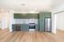Modern kitchen with sleek green cabinetry, stainless steel appliances, and elegant wood flooring.