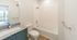 Bright and modern bathroom featuring a sleek granite countertop, elegant vanity, and contemporary bathtub.