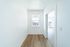 Bright and airy hallway with elegant wood flooring leading to a sunlit room through a modern doorway.