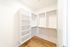 Spacious walk-in closet with built-in shelving and elegant wooden flooring, perfect for organized storage and stylish living.