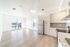 Bright and modern open-concept kitchen and living area with sleek cabinetry, stainless steel appliances, and large windows offering beautiful views.