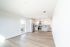 Bright open-concept kitchen with modern stainless steel appliances, light wood flooring, and ample natural light from a sunny window.