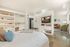 Modern open-concept studio apartment with a cozy bed, built-in shelving, chic living area, and sleek kitchenette.