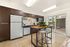 Modern kitchen with sleek dark cabinets, stainless steel appliances, and a cozy breakfast bar, seamlessly opening to a sunny patio view.