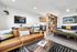 Modern studio apartment featuring a cozy leather couch, chic glass coffee table, open shelving divider, stylish decor, and inviting sleeping area with vibrant accents.