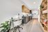 Modern apartment interior showcasing a sleek kitchen with wood cabinets and stainless steel appliances, adjacent to a cozy desk space and stylish shelving.