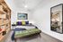Modern bedroom with stylish decor, featuring a cozy bed with navy and yellow accents, a chic green bench, and elegant shelving for a contemporary touch.