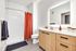Bright modern bathroom featuring a sleek vanity with wood finish, illuminated mirror, and vibrant red shower curtain.