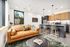 Chic apartment interior showcasing an open-plan design with a modern kitchen, cozy leather sofa, and sleek bar seating.