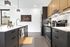 Modern kitchen with sleek black cabinetry, stainless steel appliances, and elegant pendant lighting, complemented by a stylish countertop and vibrant wall art.