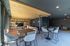 Modern lounge area with sleek bar stools, cozy seating, and stylish wooden ceiling, perfect for social gatherings.