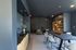 Modern and chic lounge area with stylish dark walls, sleek kitchenette, elegant pendant lighting, comfortable seating, and a sophisticated bookshelf.
