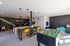 Vibrant game room featuring a foosball table, pool table with bright yellow chairs, arcade machines, and cozy bean bags for ultimate relaxation and fun.