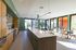 Bright, modern communal kitchen and dining area with sleek countertops and floor-to-ceiling windows overlooking a vibrant outdoor space.