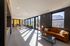 Sunlit modern lounge area with sleek sofa, stylish coffee table, and floor-to-ceiling windows offering vibrant outdoor views.