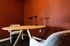 Chic home office with round wood table, stylish chairs, and dual microphones against a textured terracotta wall.