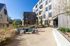 Modern apartment complex with sleek wooden exterior, featuring a vibrant outdoor patio area with comfortable seating and a communal barbecue grill.