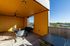 Bright and inviting covered balcony with modern furniture, featuring a vibrant yellow ceiling and walls, offering scenic views of the surrounding greenery.