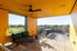 Modern terrace with vibrant orange walls, cozy seating area, and stunning cityscape views.