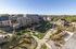 Charming modern apartment complex with unique wooden architecture, surrounded by lush greenery and winding walking paths under a clear blue sky.