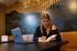 Modern workspace with cozy seating, mural backdrop, and a person writing at a table, exemplifying focus and creativity.
