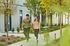 Happy couple enjoying a stroll with their dog along a lush, tree-lined walkway in a modern apartment complex.