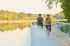 Joyful couple cycling along a scenic lakeside path surrounded by lush greenery, embodying a vibrant and active lifestyle.
