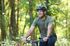 Man enjoying a bike ride through a lush green forest, smiling with a sense of adventure and freedom.