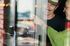 Joyful moment of friends clinking glasses with refreshing drinks, seen through a window at a vibrant cafe.