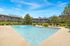 Inviting outdoor pool area surrounded by lush greenery and modern apartment buildings, offering a serene and relaxing atmosphere.